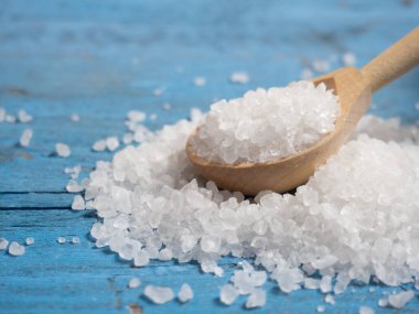 Deniz tuzu, ahşap bir kaşıkta eski ahşap bir arka planda deniz tuzu yığını.