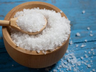 Deniz tuzu, ahşap bir kaşıkta eski ahşap bir arka planda deniz tuzu yığını.