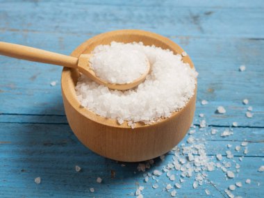 Deniz tuzu, ahşap bir kaşıkta eski ahşap bir arka planda deniz tuzu yığını.