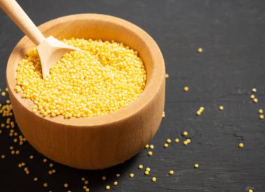 Millet. Millet ahşap bir kaşıkta kase ve ahşap bir mutfak masasında.