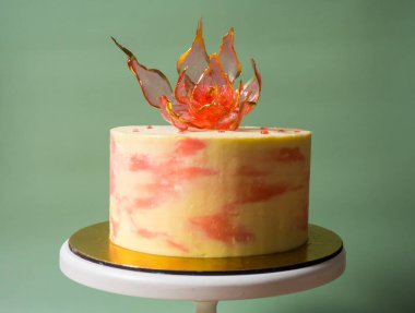 Pastanın üzerinde soluk yeşil bir arka planda, yenilebilir kırmızı bir izomalt çiçeği.