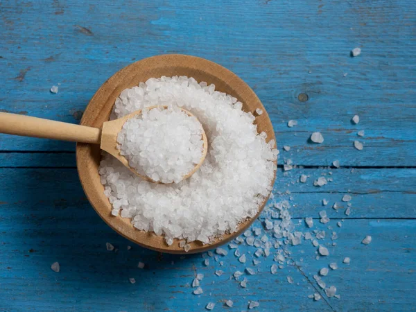 sea salt, a pile of sea salt in a wooden spoon on an old wooden background close-up