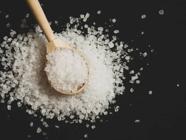 sea salt, a pile of sea salt in a wooden spoon on an old wooden background close-up