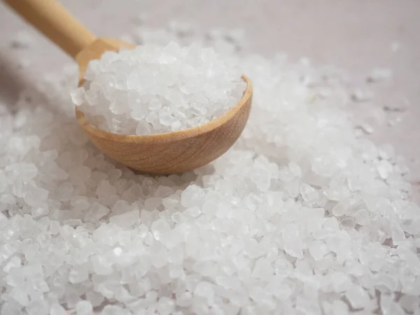 sea salt, a pile of sea salt in a wooden spoon on a light concrete background