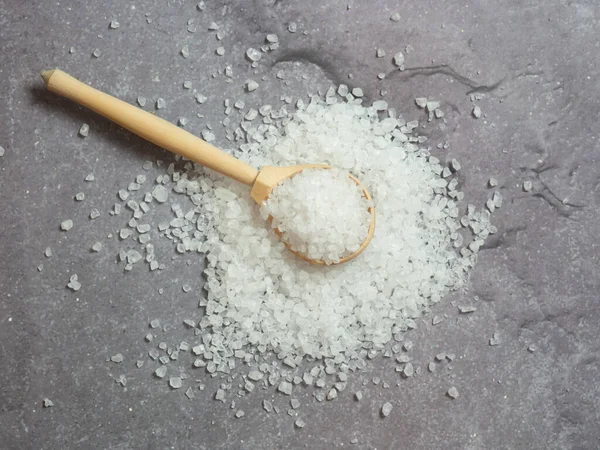 sea salt, a pile of sea salt in a wooden spoon on a light concrete background