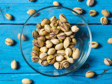 Eski ahşap bir masanın üzerinde temiz cam bir kasede fıstıklar atmosferik bir kırsal kompozisyon, bir kopya alanı.