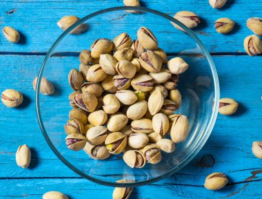 Eski ahşap bir masanın üzerinde temiz cam bir kasede fıstıklar atmosferik bir kırsal kompozisyon, bir kopya alanı.