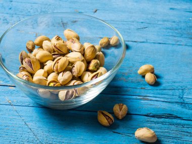 Eski ahşap bir masanın üzerinde temiz cam bir kasede fıstıklar atmosferik bir kırsal kompozisyon, bir kopya alanı.