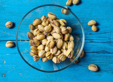 Eski ahşap bir masanın üzerinde temiz cam bir kasede fıstıklar atmosferik bir kırsal kompozisyon, bir kopya alanı.