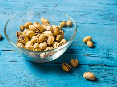 Eski ahşap bir masanın üzerinde temiz cam bir kasede fıstıklar atmosferik bir kırsal kompozisyon, bir kopya alanı.