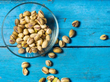 Eski ahşap bir masanın üzerinde temiz cam bir kasede fıstıklar atmosferik bir kırsal kompozisyon, bir kopya alanı.