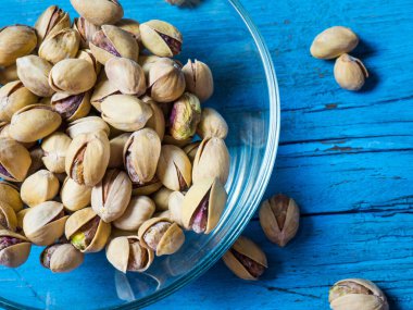 Eski ahşap bir masanın üzerinde temiz cam bir kasede fıstıklar atmosferik bir kırsal kompozisyon, bir kopya alanı.