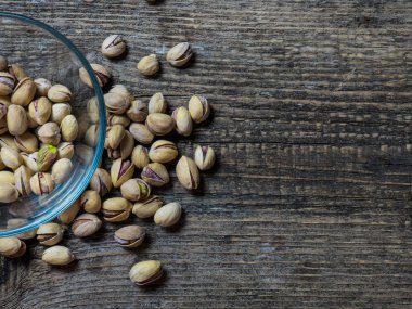 Eski ahşap bir masanın üzerinde temiz cam bir kasede fıstıklar atmosferik bir kırsal kompozisyon, bir kopya alanı.