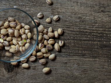 Eski ahşap bir masanın üzerinde temiz cam bir kasede fıstıklar atmosferik bir kırsal kompozisyon, bir kopya alanı.