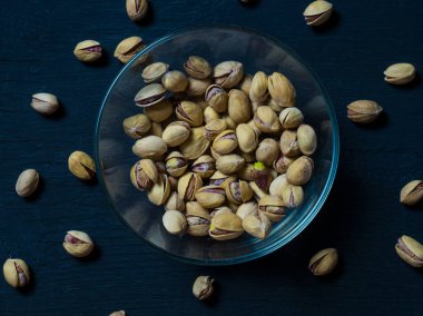 Eski ahşap bir masanın üzerinde temiz cam bir kasede fıstıklar atmosferik bir kırsal kompozisyon, bir kopya alanı.