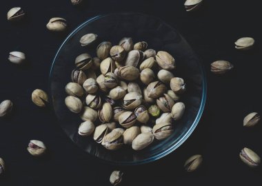 Eski ahşap bir masanın üzerinde temiz cam bir kasede fıstıklar atmosferik bir kırsal kompozisyon, bir kopya alanı.