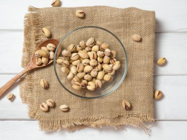 Eski ahşap bir masanın üzerinde temiz cam bir kasede fıstıklar atmosferik bir kırsal kompozisyon, bir kopya alanı.