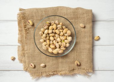 Eski ahşap bir masanın üzerinde temiz cam bir kasede fıstıklar atmosferik bir kırsal kompozisyon, bir kopya alanı.