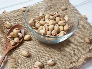 Eski ahşap bir masanın üzerinde temiz cam bir kasede fıstıklar atmosferik bir kırsal kompozisyon, bir kopya alanı.