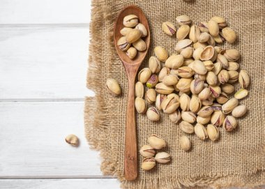 Pistachios 'u ahşap bir kaşıkta, ahşap bir masada fotokopi alanı olan kapalı bir manzara..