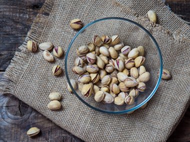 Eski ahşap bir masanın üzerinde temiz cam bir kasede fıstıklar atmosferik bir kırsal kompozisyon, bir kopya alanı.