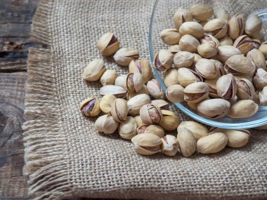 Eski ahşap bir masanın üzerinde temiz cam bir kasede fıstıklar atmosferik bir kırsal kompozisyon, bir kopya alanı.