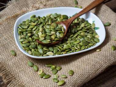 Tahta bir masadaki tahta kaşıkta balkabağı tohumları. metin alanı kopyalanıyor