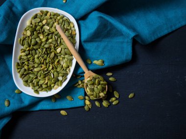 Beyaz kasede kabak çekirdeği ve tahta kaşık, yakın plan siyah ahşap arka plan. metin alanı kopyalanıyor