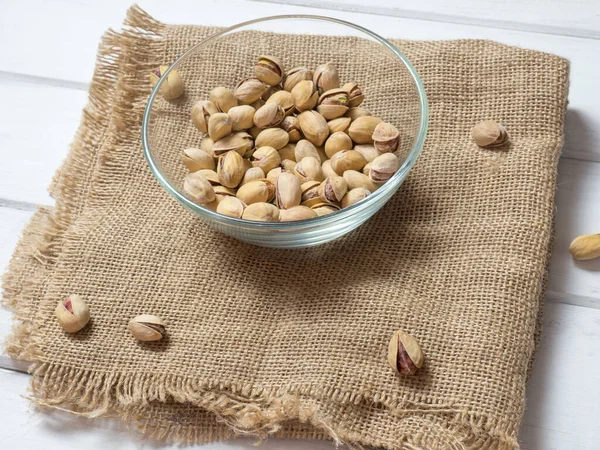 Eski ahşap bir masanın üzerinde temiz cam bir kasede fıstıklar atmosferik bir kırsal kompozisyon, bir kopya alanı.