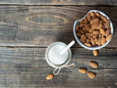 bir şişe badem sütü ve sade ahşap arka planda badem ezmesi.