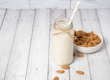 beyaz ahşap bir masada badem ve badem sütü