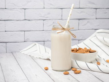 beyaz ahşap bir masada badem ve badem sütü