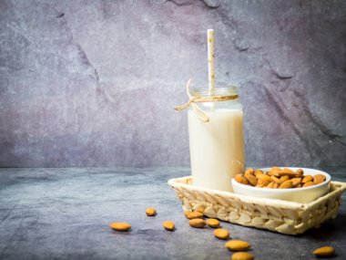 Şişedeki badem sütü ve tahta kasedeki bademler, metin için arka plandaki siyah taş kopyalama alanı.