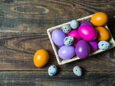 Eski ahşap bir arka planda sepetteki renkli Paskalya yumurtaları.