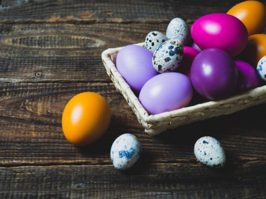 Eski ahşap bir arka planda sepetteki renkli Paskalya yumurtaları.