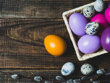 Eski ahşap bir arka planda sepetteki renkli Paskalya yumurtaları.