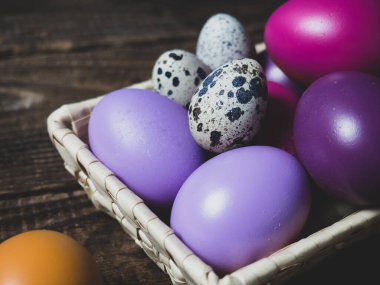 Eski ahşap bir arka planda sepetteki renkli Paskalya yumurtaları.