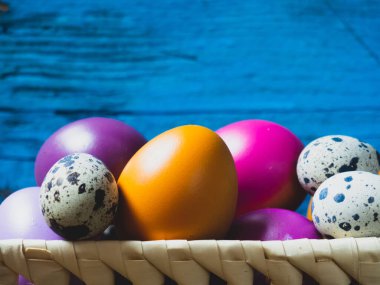 Eski ahşap bir arka planda sepetteki renkli Paskalya yumurtaları.