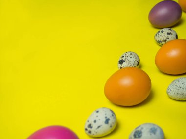Sarı arka planda parlak renkli Paskalya yumurtaları. Parlak bir festival kompozisyonu. Tebrik kartı için arkaplan.