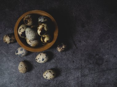 Tahta bir kasede bıldırcın yumurtası. Koyu beton bir arka planda. Üst Manzara. Kopyalamak için boş alan.