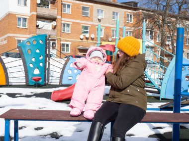 Bir anne ve küçük bir çocuk oyun parkında yürüyor.