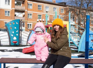 Bir anne ve küçük bir çocuk oyun parkında yürüyor.