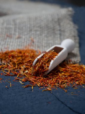 Siyah arka planda, tahta kaşıkta kurumuş safran baharatları.