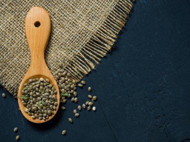 Tahta bir kaşıkta siyah bir masada kenevir tohumu.