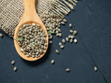 Tahta bir kaşıkta siyah bir masada kenevir tohumu.