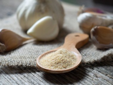 Lezzetli sarımsak soğanları ve karanfiller bir kaşık dolusu sarımsak tozu ile ahşap bir masada