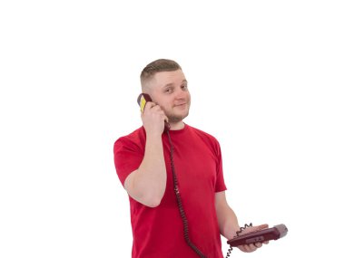 Spor elbiseli yakışıklı bir gencin portresi, eski bir sabit telefonla konuşuyor, ahizeyi kulağının yanında tutuyor. izole edilmiş beyaz arkaplanda