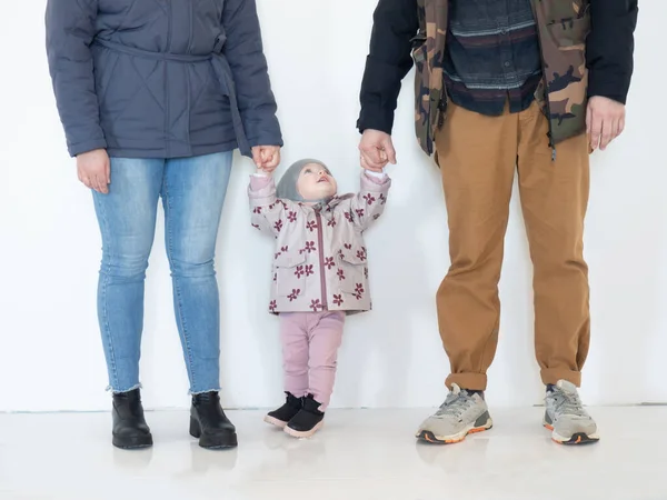 Modern young family, mom, dad and their eight-month-old daughter hold hands