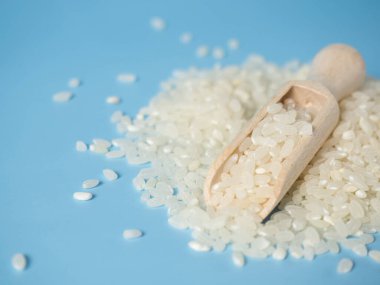 Mavi arka planda tahta kaşıkta pirinç taneleri