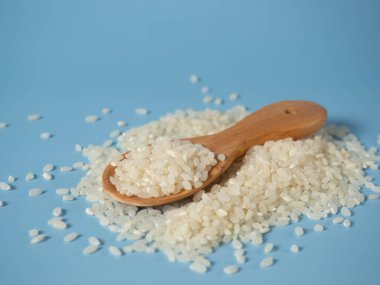 Mavi arka planda tahta kaşıkta pirinç taneleri